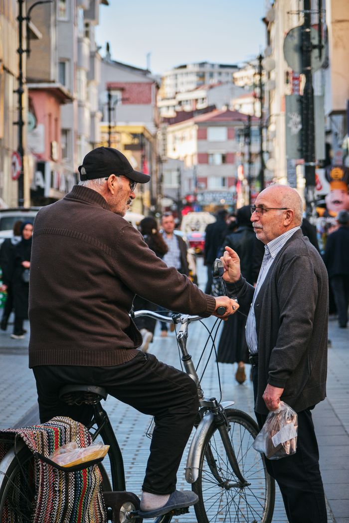 Two senior men chatting on a bustling street in İstanbul, vibrant city life.