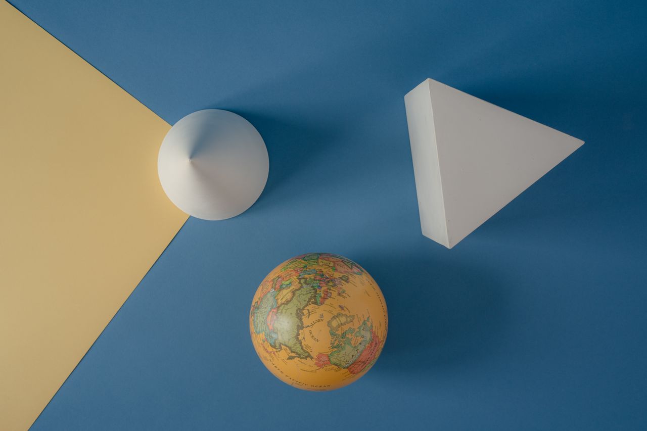 The Art of Drawing Readers In: Your attractive post title goes here Abstract arrangement of geometric shapes and a globe on a colorful background.